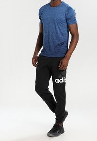 Blåmelerad kortärmad t-shirt som matchas med svarta joggers med en vit logotyp, elastiska mudd och en slim fit-design.