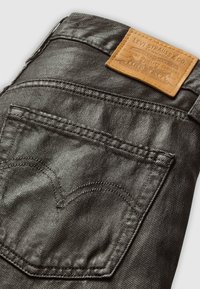 Zwarte denim jeans met een leren merkpatch op de tailleband, zichtbare stiksels en een kenmerkend gebogen achterzakdetail.