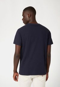 Marineblauwe t-shirt met korte mouwen en een ronde hals. Van katoen, met een relaxte pasvorm. Gemaakt met lichtgekleurde jeans met logo-detail op de achterkant.