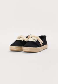 Espadrillas in canvas nere con lacci beige, dotate di una suola in juta intrecciata e bordi sfilacciati. Design semplice con una silhouette classica.