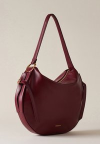 Borsa a spalla in pelle color burgundy con forma arrotondata, dettagli in metallo dorato e chiusura con zip laterale. Include una tracolla piatta per un facile trasporto.