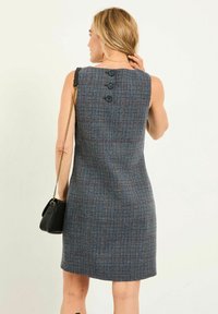 Ärmelloses Kleid aus marineblauem Hahnentwist-Stoff mit strukturiertem Muster, das auf der Rückseite drei schwarze Knöpfe hat. Glatte Silhouette und knielang.