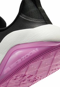 Chaussure de sport noire avec une tige texturée et une semelle intermédiaire blanche. La semelle extérieure en caoutchouc rose présente un motif de bande de roulement distinct et un détail embossé "AIR ZOOM".