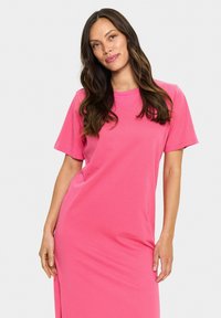 Rožinė medvilninė T-shirt suknelė su trumpomis rankovėmis, laisvu siluetu, apvalia iškirpte ir šoniniu plyšiu. Sklandi tekstūra ir laisvalaikio dizainas.