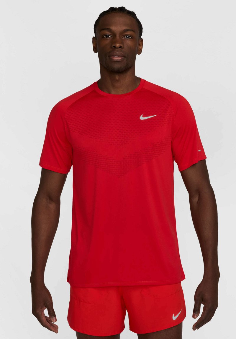 Crvena atletska majica kratkih rukava izrađena od laganog materijala, s teksturiranim uzorkom i srebrnim Nike logotipom na prsima.