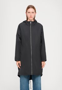 Zwarte lichtgewicht jas met een capuchon, lange mouwen, rits aan de voorkant en een rechte snit, gecombineerd met blauwe spijkerjeans. Glad textuur van de stof.