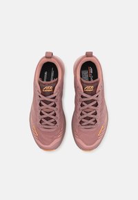 Light pink athletic shoes with a textured upper, reinforced toe, and orange accents. Features a lace-up closure and pull tab for easy wear.