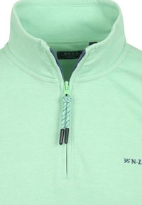Fleece pullover in lichtgroen met een half-rits ontwerp, voorzien van een marineblauwe rits, decoratieve koord en subtiel logo aan de zijkant.