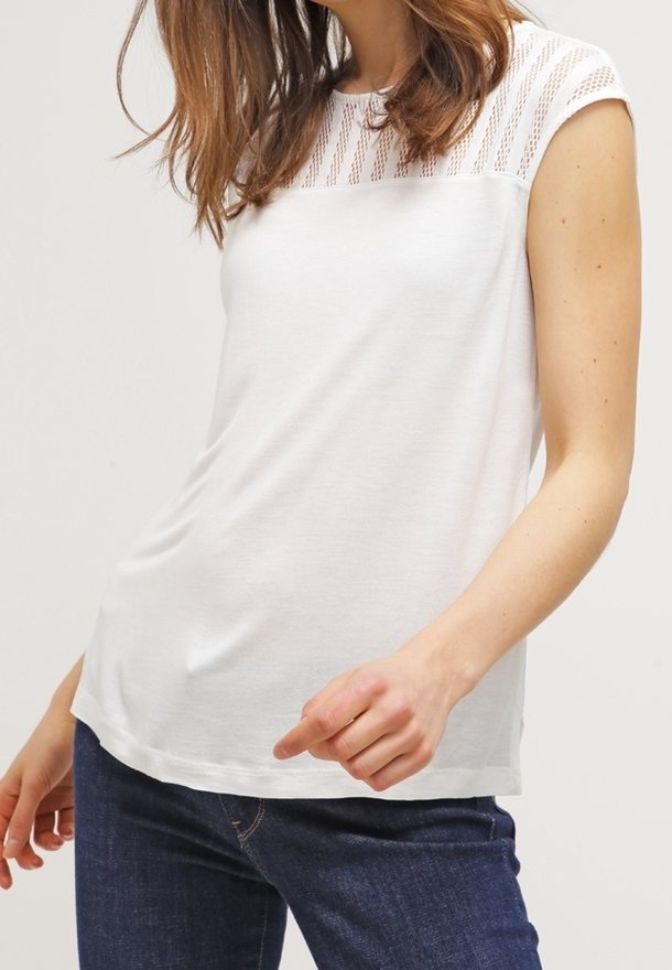 Vit kortärmad topp med en texturerad stickad panel på axlarna, med en avslappnad passform och mjukt tyg. Bar med mörka jeans.