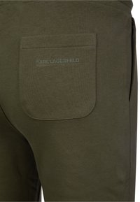 Olivgröna joggers med en bakficka med präglad "KARL LAGERFELD"-logotyp, tillverkade av mjukt bomullsmaterial med en subtil textur.