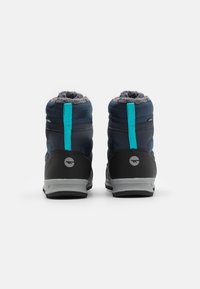 Botas aislantes de color navy con suela negra, forro de piel de oveja gris y acento turquesa en la parte trasera. Diseño acolchado para calidez y comodidad.