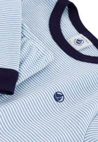 Blue and white striped cotton top with navy ribbed neckline and cuffs, featuring a small logo accent on the chest. Soft texture.