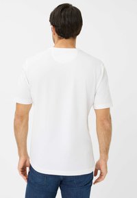 T-shirt bianco a maniche corte realizzato in cotone liscio. Presenta un collo rotondo e una vestibilità casual, con un retro semplice e senza loghi o grafiche visibili.
