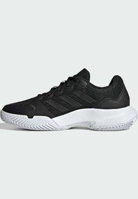 Scarpe da ginnastica nere con tomaia in tessuto texture, tre strisce nere di lato e suola in gomma bianca con motivo a zigzag.