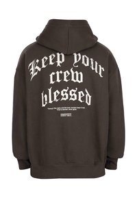 Brauner Hoodie mit weißem gotischem Text auf dem Rücken, der "Halte deine Crew gesegnet" liest, und kleinerem Text darunter über Vertrauen und Loyalität.