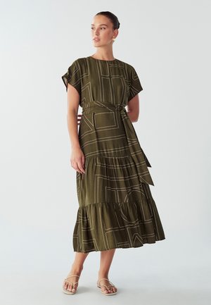 Olive green midi dress with short sleeves, geometric white patterns, a belted waist, and a tiered skirt. Soft, textured fabric.