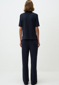 Completo due pezzi navy composto da una maglietta a maniche corte con una vestibilità comoda e pantaloni a gamba larga, realizzati in un tessuto leggero e strutturato.