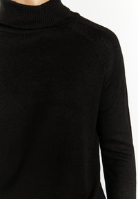 Schwarzer Strickrollkragenpullover mit Rippstruktur und Raglanärmeln, ausgestattet mit einem hohen Kragen und taillierter Passform.