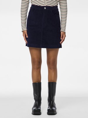 Marineblå kordfløjl mini-skirt med frontknaplukning, to sidelommer og lige pasform, kombineret med knæhøje sorte støvler.