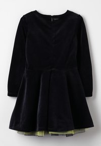 Navy blue velvet dress with long sleeves and a flared skirt. Features a back zipper and layered green tulle underskirt.