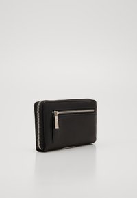 Schwarze Lederbrieftasche mit strukturiertem Oberflächendesign, auffälligem silbernen Reißverschluss und einer äußeren Reißverschlusstasche für zusätzlichen Stauraum.
