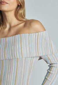 Schulterfreies Oberteil mit vertikalen Streifen in Pastellfarben und dünnen metallischen Akzenten. Der Stoff wirkt gerippt und hat eine strukturierte Oberfläche.