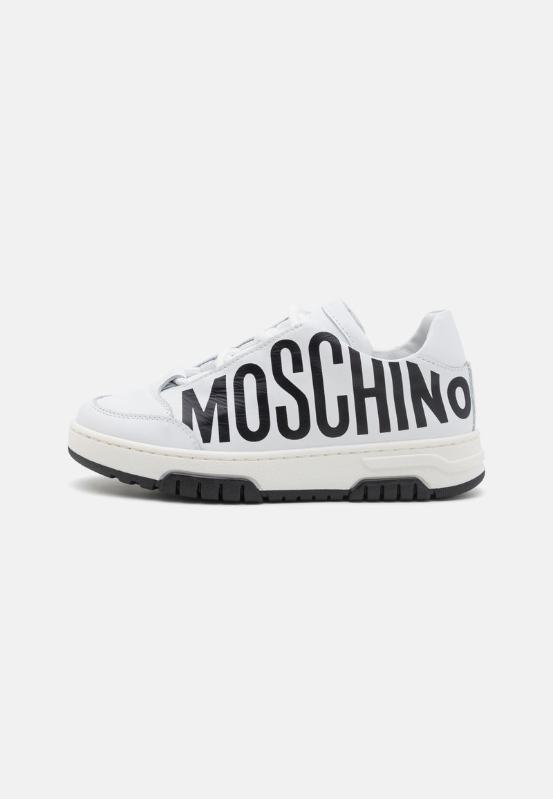 Sneaker en cuir blanc avec lettrage "MOSCHINO" noir, surface texturée, bout rond, semelle en caoutchouc blanc et accents noirs sur le bas.