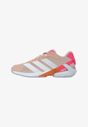 Zapato deportivo rosa claro con franjas blancas de Adidas, acentos en la suela en naranja y gris, y una lengüeta en el talón de color rosa brillante.