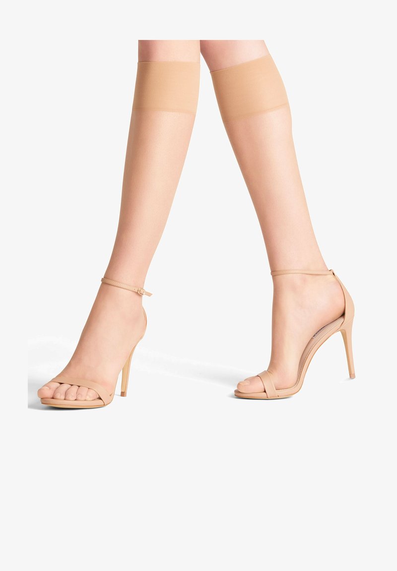 Nude sandały na wysokim obcasie o minimalistycznym designie, z cienkim paskiem na kostce i otwartym noskiem. Gładka faktura i strukturna forma.