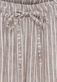 Lys brun og hvid stribet stof; har en elastisk talje med snorelukning. Teksturen ser vævet og åndbar ud.