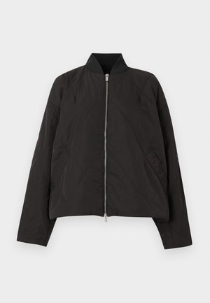 Veste bomber noire matelassée avec fermeture éclair à l'avant, poches latérales et col côtelé, présentée sur un fond clair uni.