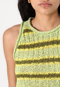 Top en tricot de couleur vert clair avec des motifs rayés horizontaux en vert foncé et jaune. Tissu texturé avec un col à côtes.