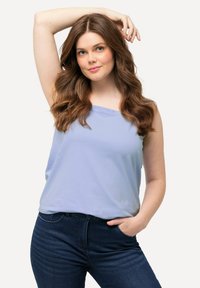Lichtblauw mouwloos topje van zachte stof, gecombineerd met donkerblauwe jeans. Het topje heeft een relaxte pasvorm en een ronde halslijn.