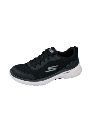 Zapatilla deportiva negra y gris con suela blanca, tejido de malla, cierre de cordones en la parte delantera y logotipo de la marca "S" en el lateral.