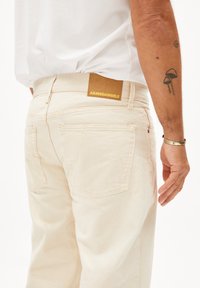 Lichtbeige spijkerbroek van denim, met een bruin leren label met het reliëf 'ARMEDANGELS' logo, achterzakken en een casual pasvorm.