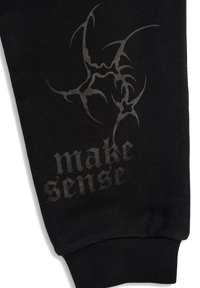 Czarne dresy z fakturowanym wzorem, z szarym graficznym nadrukiem przedstawiającym stylizowane kształty oraz frazą "make sense" w wyraźnym, pogrubionym napisie.