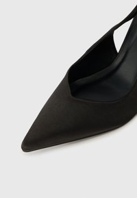 Μαύρο εσπαντρίγια σλιπ-ποντ με μυτερή μύτη, φτιαγμένο από αδιάβροχο ύφασμα και με χαμηλό τακούνι, σε λευκό φόντο.