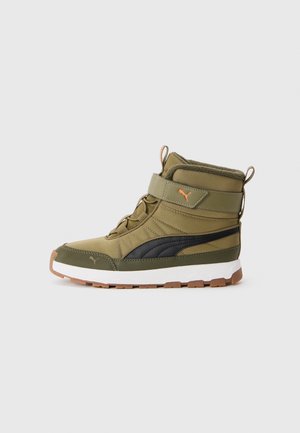Botte d'hiver montante vert olive avec bande noire Puma, fermeture par sangle et semelle blanche avec semelle brune, sur fond uni.