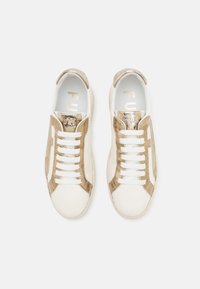 Baskets blanches avec des accents métalliques dorés, présentant une tige en cuir lisse, des panneaux latéraux texturés et des lacets plats blancs.