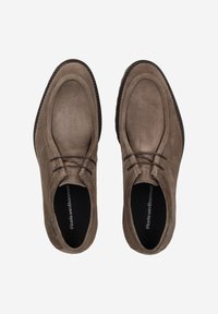 Chaussures en daim marron avec un bout arrondi et un détail de laçage. Présentent une surface texturée et une semelle en caoutchouc foncé avec des coutures d'accent.