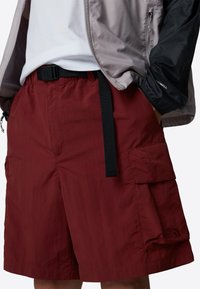 Red cargo shorts made of lightweight fabric, featuring a black belt, multiple pockets, and The North Face logo on the side.
