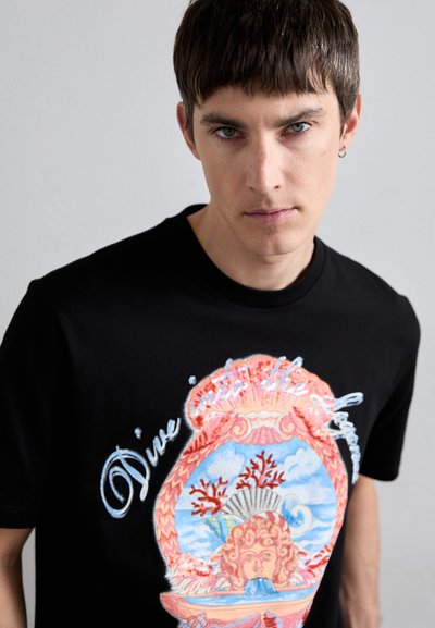 T-shirt en coton noir avec un graphique coloré représentant un visage mythique dans une coquille avec des coraux, et le texte "Plongez dans le Silence."