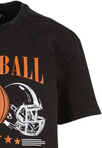 Sort oversized T-shirt med orange "FOOTBALL" tekst, et hvidt fodboldhjelm grafik og en illustration af en basketball med stjerne accenter.