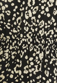 Tessuto nero con motivo a stampa leopardo bianca, caratterizzato da una vita arricciata e una texture plissettata, che mette in mostra un materiale morbido e leggero.
