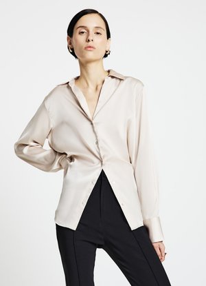 Chemise satinée beige clair à manches longues, avec une patte de boutonnage à l'avant et un col classique, présentant une texture lisse et une coupe légèrement ample.