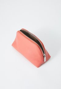 Pochette in pelle corallo con finitura testurizzata, forma triangolare e zip argentata, con interni marroni.