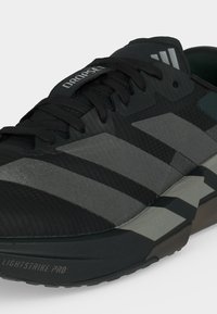 Μαύρο και γκρι αθλητικό παπούτσι Adidas με τη λέξη "DROPSET" στη γλώσσα και "LIGHTSTRIKE PRO" στη σόλα, με σχέδιο με κορδόνια.