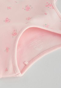 Hele heleroosa bodi väikese lillemustriga, valmistatud pehmest puuvillast. Omadused: ümar kaelus ja õmmeldud servad. Alumisel küljel nähtav silt.