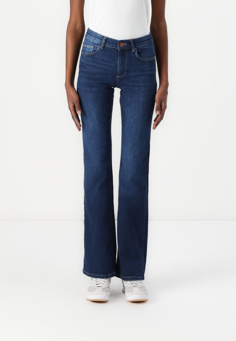 Vaqueros azules acampanados de cintura alta, con bolsillos delanteros y cierre de botón. Hechos de denim con una textura suave y ligero estiramiento.