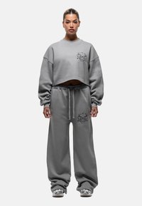 Felpa grigia corta e pantaloni della tuta abbinati, larghi, con accenti grafici, realizzati in materiale morbido, dotati di vita con cordino.